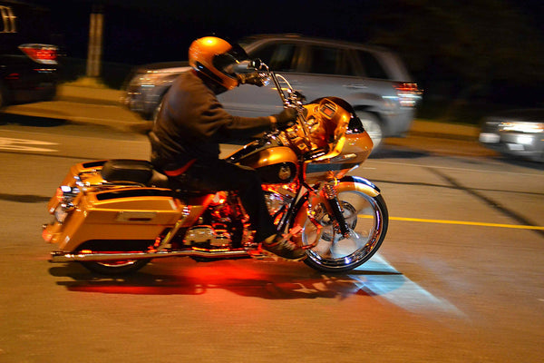 Custom orange Harley Road Glide bagger riding at night with motion blur